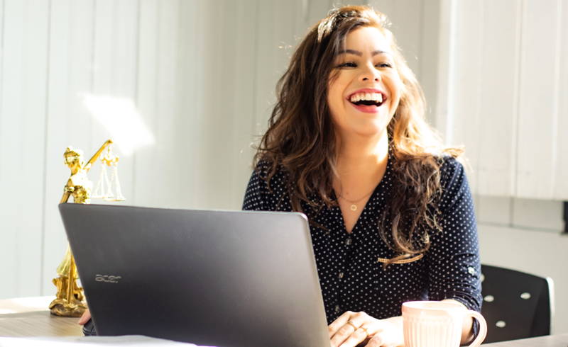 Woman laughing while sitting at her laptop