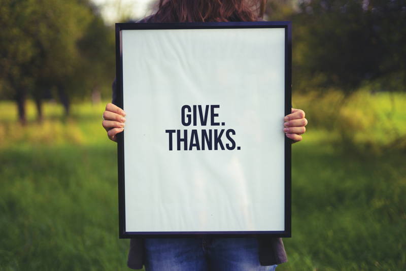 Woman holding "give thanks" sign