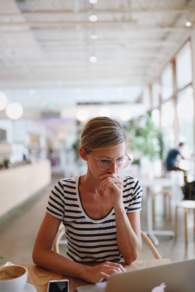 Woman sitting in cafe with laptop, focusing closely on work.