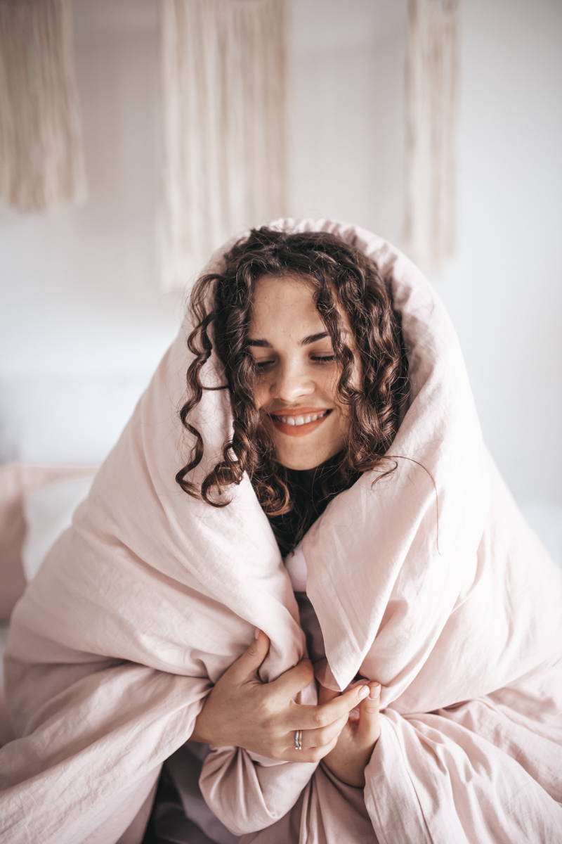 woman smiling under a blanket