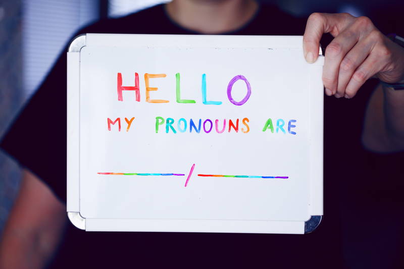Person holding a whiteboard with pronouns