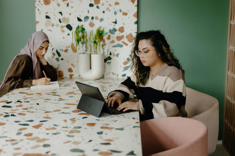 Two self-aware women working in an office