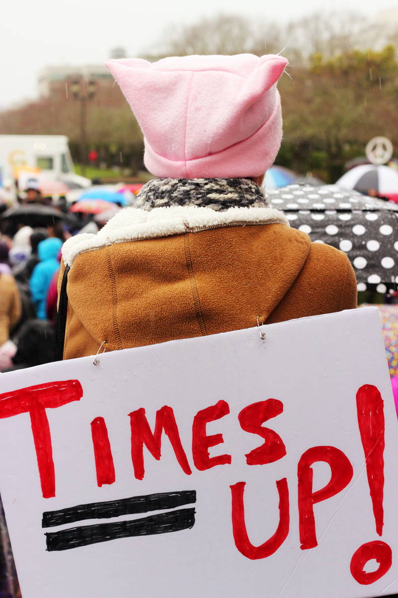 Woman at a 2018 Women's March holding a "time's up" sign