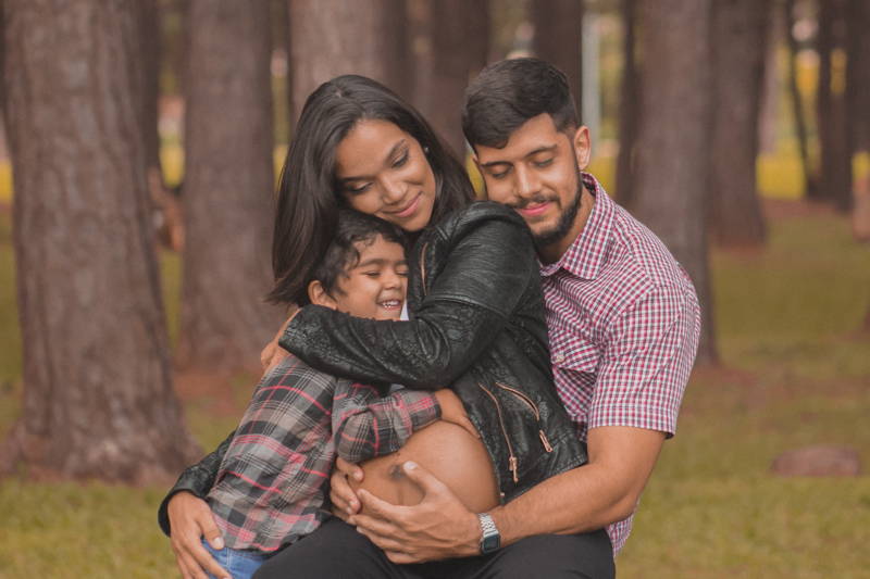 Family hugging pregnant woman while on maternity leave