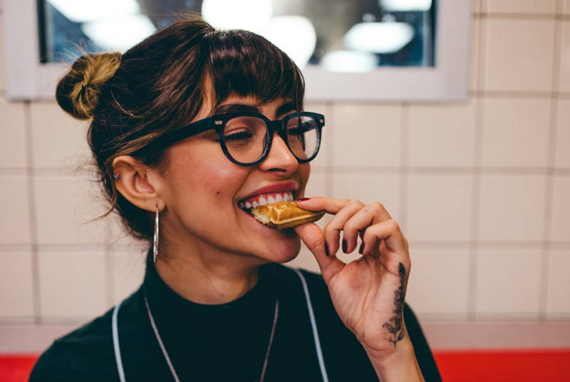 Young woman eating pizza and smiling to celebrate her salary negotiation