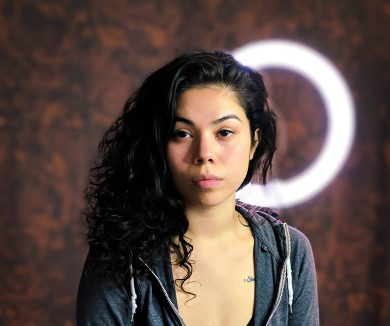 overwhelmed woman staring straight into camera with ring light behind her